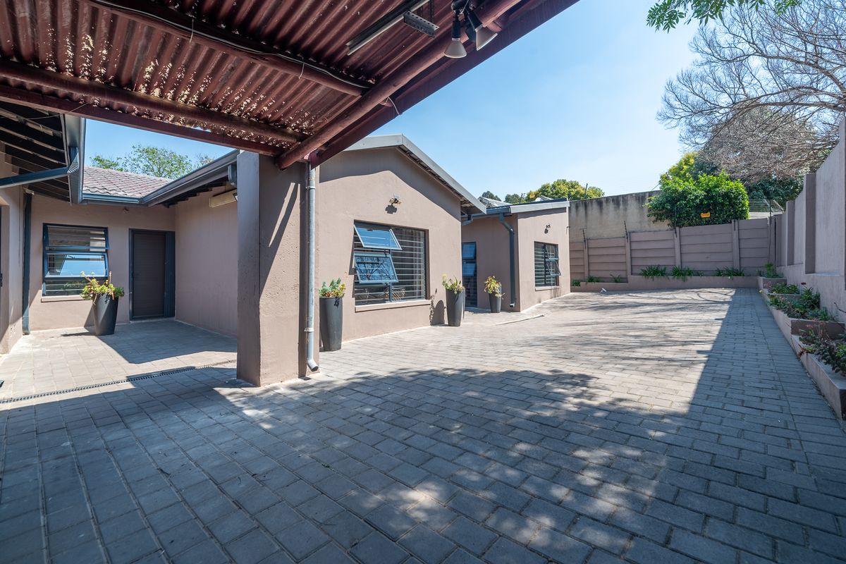A spacious paved rear courtyard area featuring a covered patio section, secure boundary walls, and well-maintained exterior finishes.