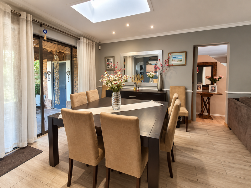A well-lit dining room featuring tile flooring, a skylight, and large sliding glass doors that provide access to an outdoor patio area.