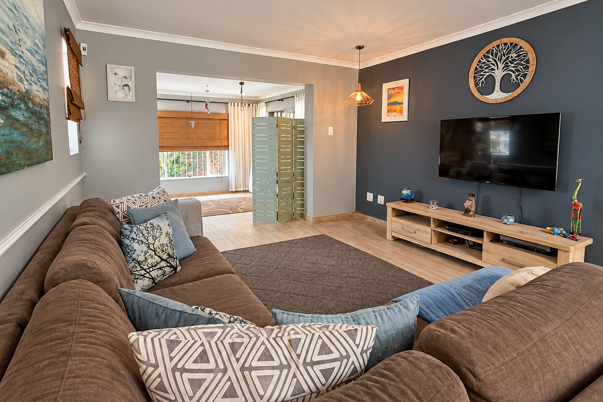 A comfortable living room featuring tiled flooring, a dark blue accent wall, and a neutral color palette with a view into an adjacent space.