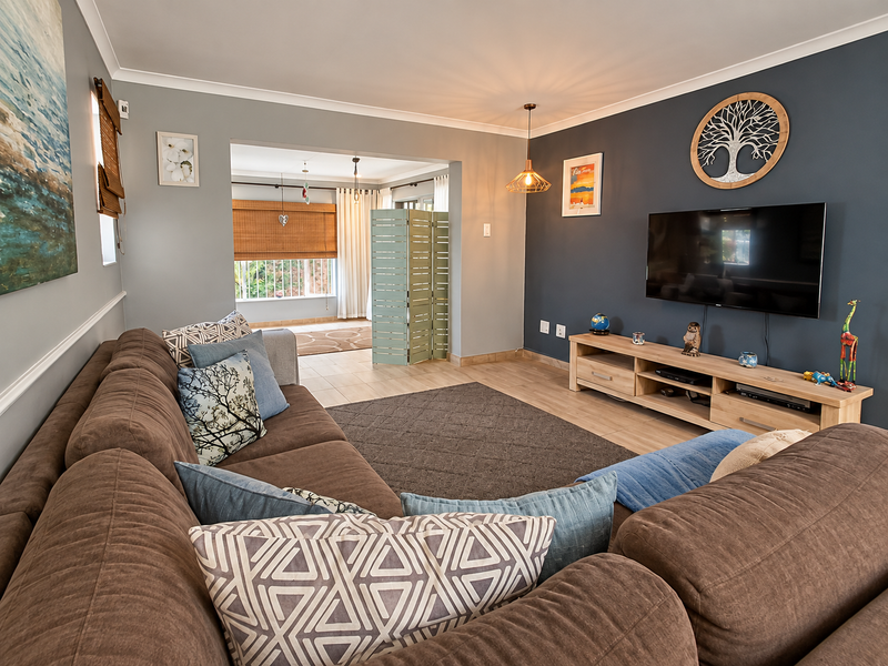 A comfortable living room featuring tiled flooring, a dark blue accent wall, and a neutral color palette with a view into an adjacent space.