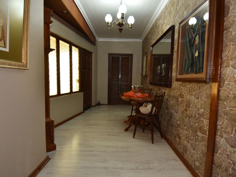 Spacious hallway featuring a stone-clad feature wall, timber-panelled ceiling, and light-toned laminate flooring, creating a warm and traditional entrance area.