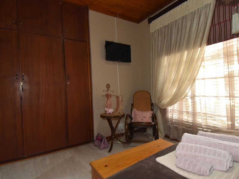 A bedroom featuring built-in wooden cupboards, a wooden ceiling, and laminate flooring, offering a functional space with traditional finishes.