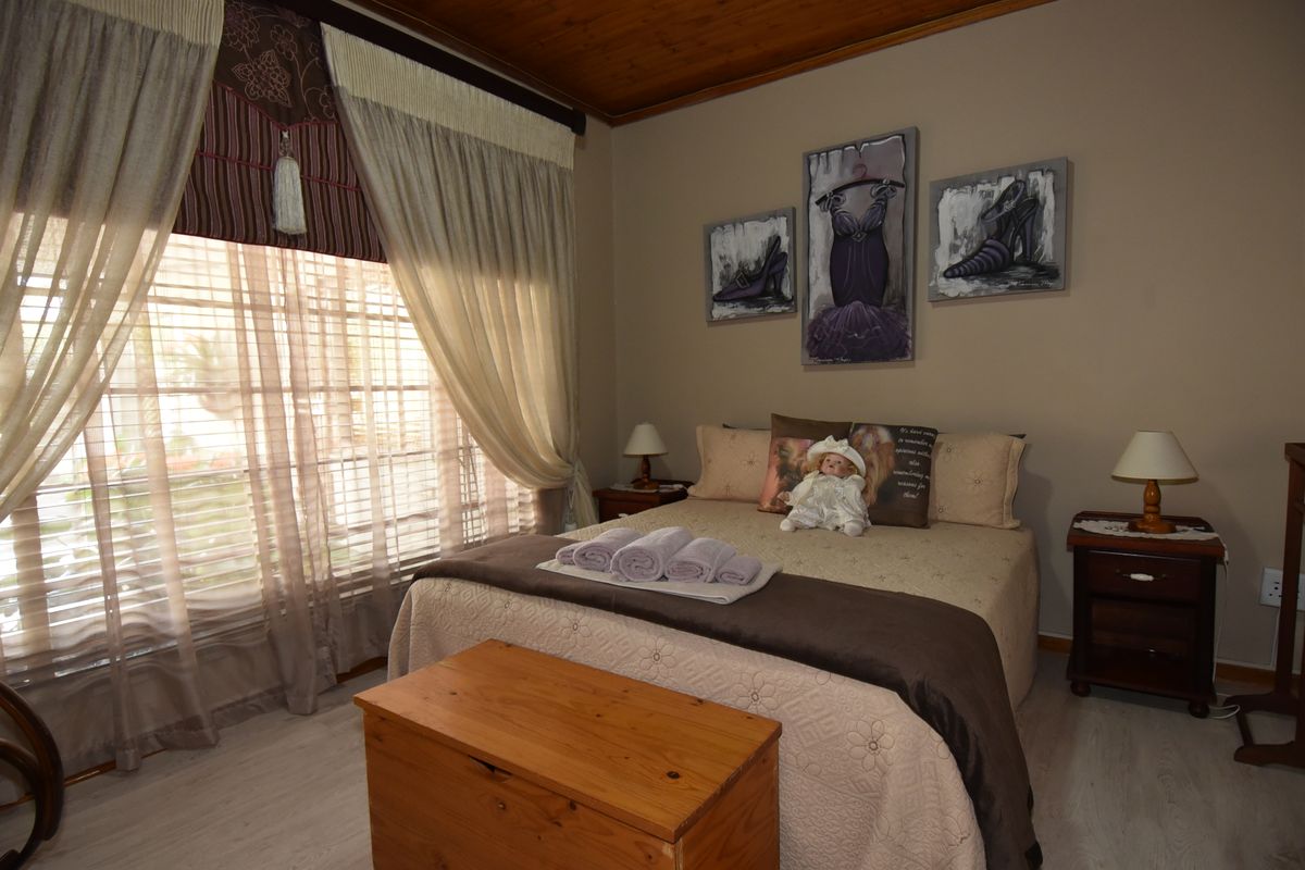 A cozy bedroom featuring a timber ceiling and light-toned laminate flooring, offering a warm and inviting atmosphere.