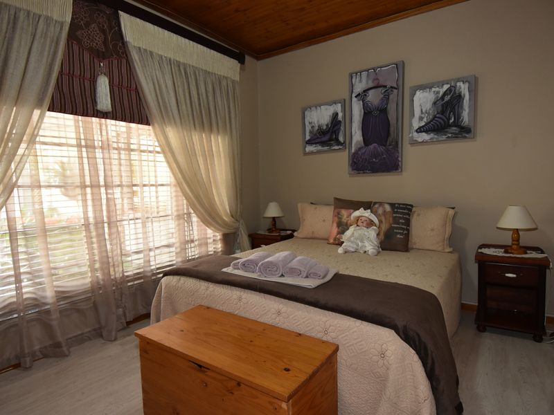 A cozy bedroom featuring a timber ceiling and light-toned laminate flooring, offering a warm and inviting atmosphere.