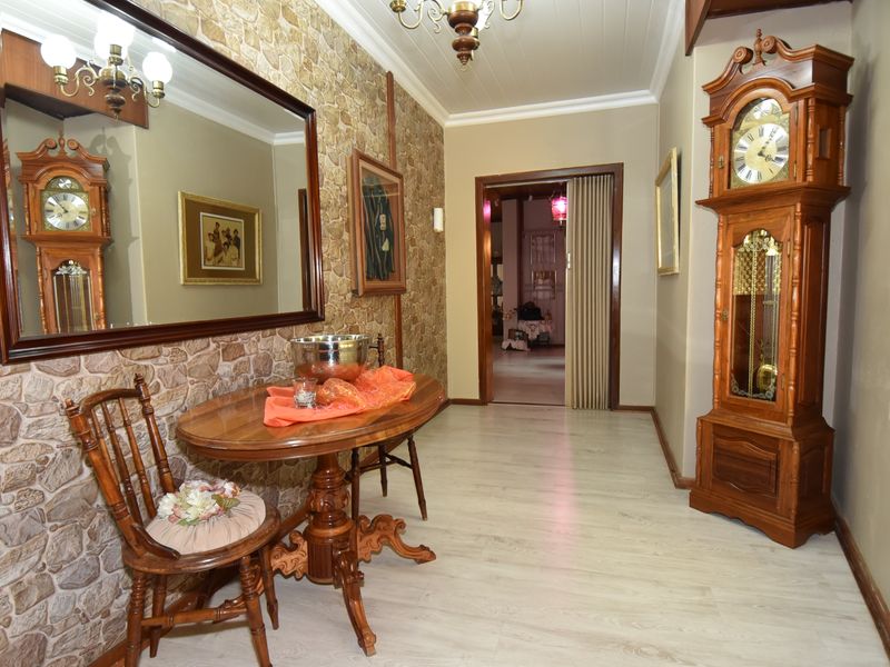 A hallway featuring a stone veneer accent wall, light-toned laminate flooring, and a tongue and groove ceiling, leading through a folding door to another room.