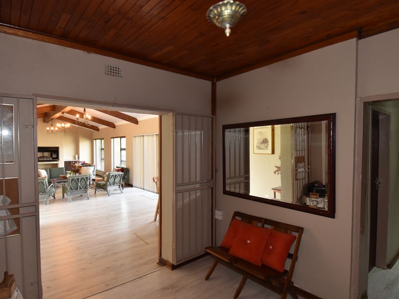 A welcoming hallway featuring timber ceilings and laminate flooring, providing a clear view into the spacious open-plan living area beyond.
