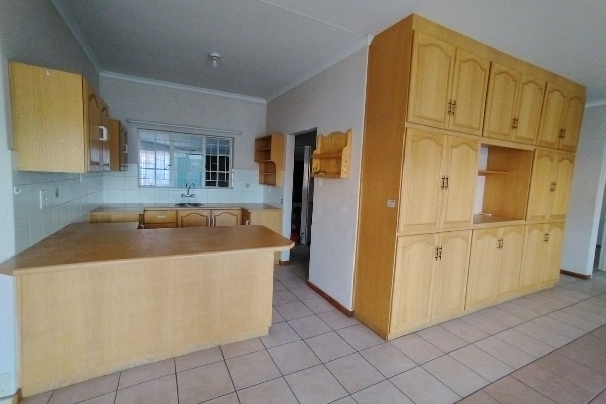 A spacious kitchen featuring extensive built-in wooden cabinetry, laminate countertops, and tiled flooring, offering a functional layout with ample storage space.