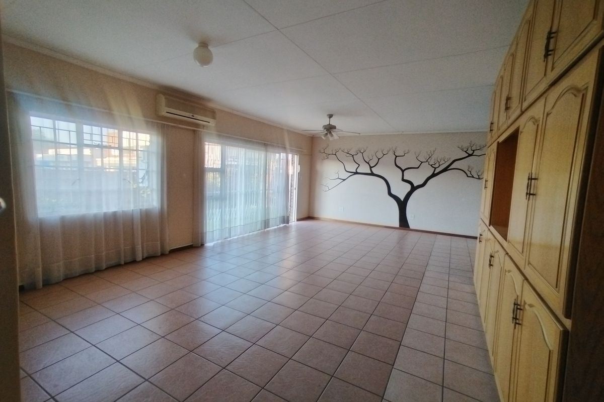Spacious living area featuring tiled flooring, built-in storage cabinetry, a ceiling fan, and split-system air conditioning with access to the exterior via sliding doors.