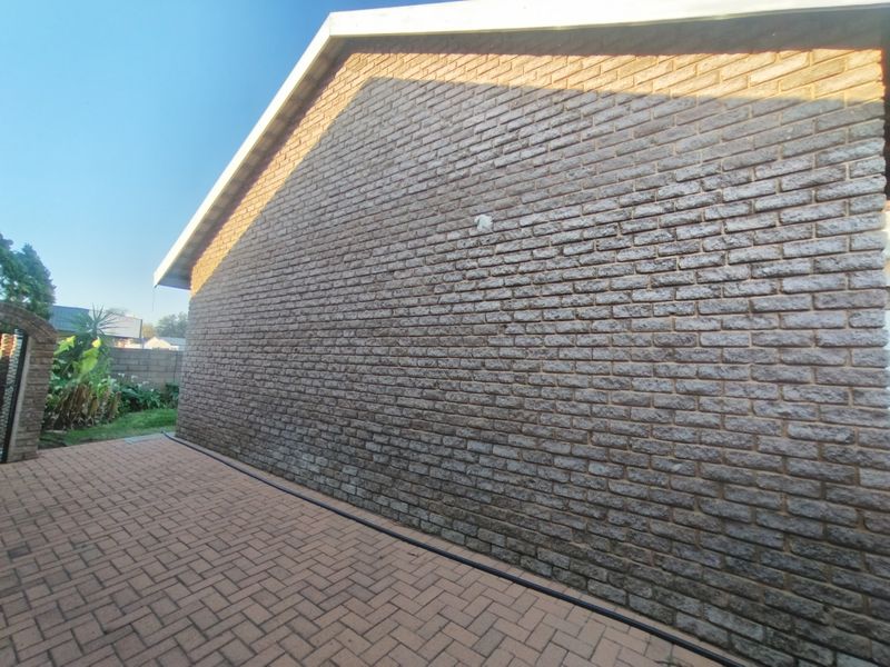 A view of the rear exterior brick facade and paved patio area of the house.