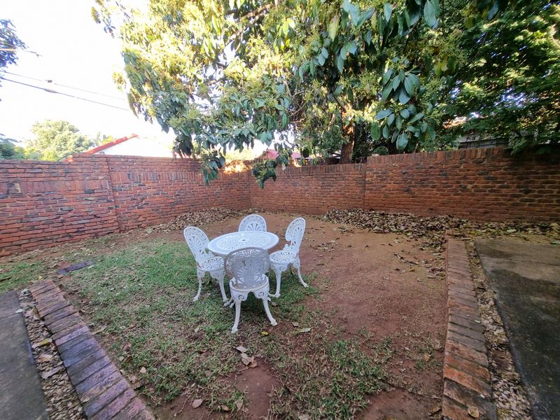 A private rear garden area enclosed by a traditional red brick boundary wall with established tree cover.