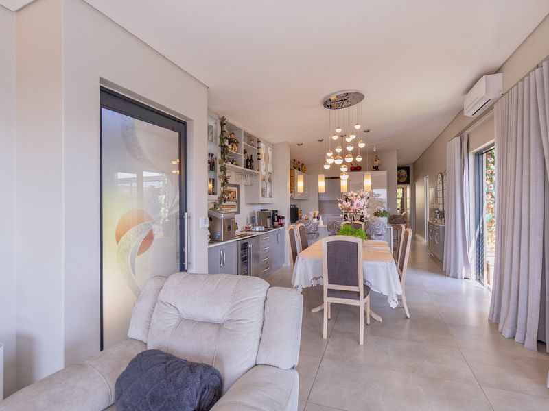 Spacious open-plan living and dining area featuring modern tiled flooring, contemporary pendant lighting, and seamless access to outdoor spaces through sliding glass doors.