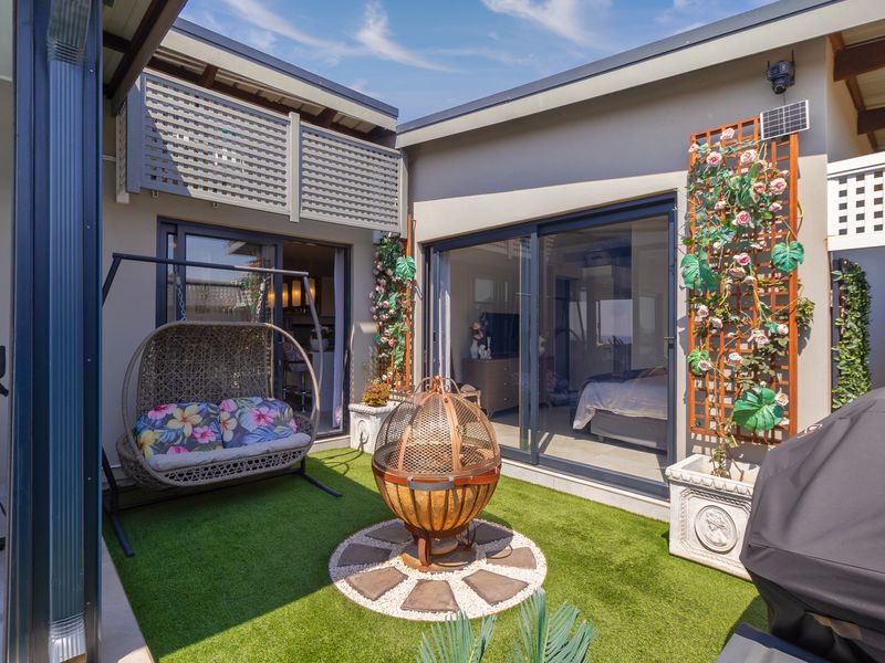 A well-maintained enclosed patio area featuring artificial turf, sliding glass doors providing indoor-outdoor flow, and decorative trellis panels.