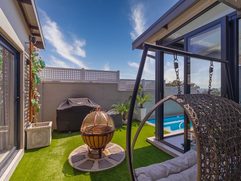 A well-maintained outdoor patio area featuring artificial turf, a swimming pool, and modern sliding glass doors connecting to the interior living space.