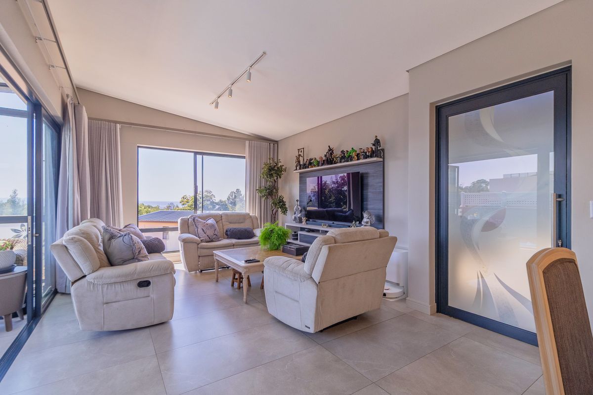 Spacious living room featuring large sliding glass doors, neutral tiled flooring, and a modern built-in media wall unit with integrated lighting.