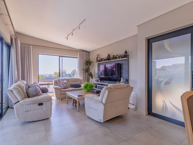Spacious living room featuring large sliding glass doors, neutral tiled flooring, and a modern built-in media wall unit with integrated lighting.