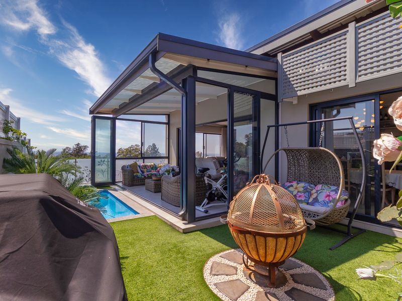 A modern covered patio area featuring glass sliding doors, a small plunge pool, and artificial turf, providing a seamless indoor-outdoor living space.