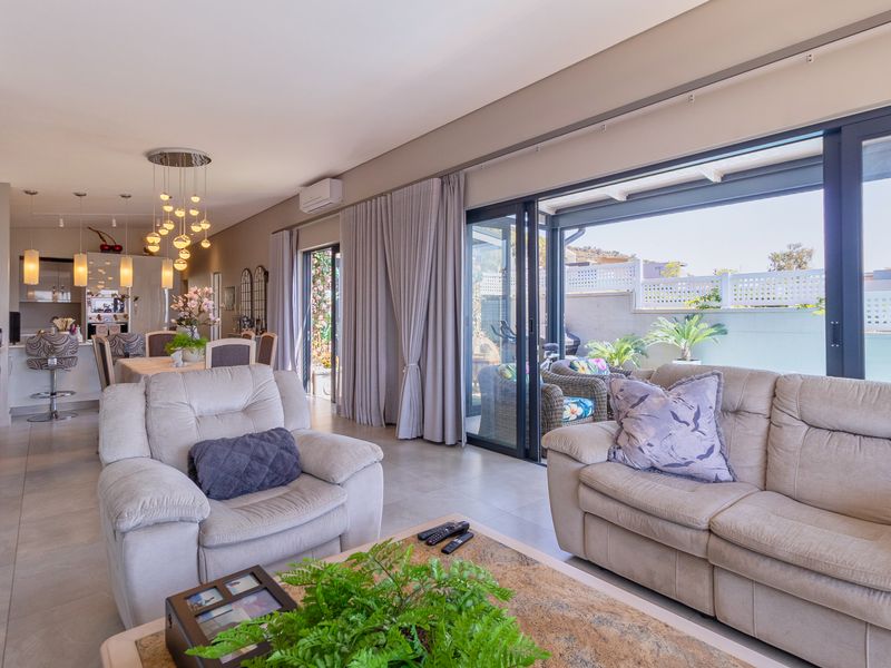 Spacious open-plan living and dining area featuring modern tiled floors, recessed lighting, and large sliding glass doors leading to an outdoor patio.