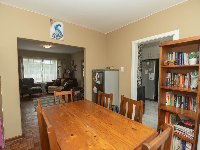 Open plan dining area featuring parquet flooring, leading into a separate kitchen space and adjacent living room.