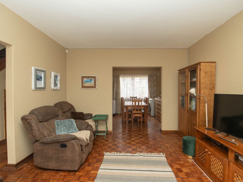 Open plan living and dining area featuring traditional parquet flooring and neutral wall tones, providing a functional and connected layout.