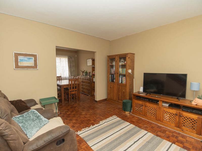 Open plan living and dining area featuring traditional parquet flooring and neutral wall tones, providing a functional and connected layout.