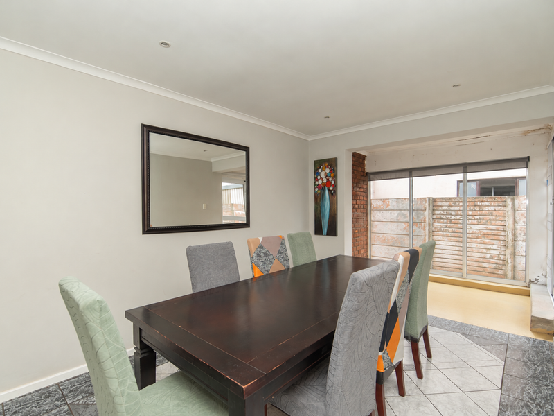 Dining room featuring tiled flooring, recessed lighting, and a sliding glass door providing access to an outdoor area with an exposed brick accent.