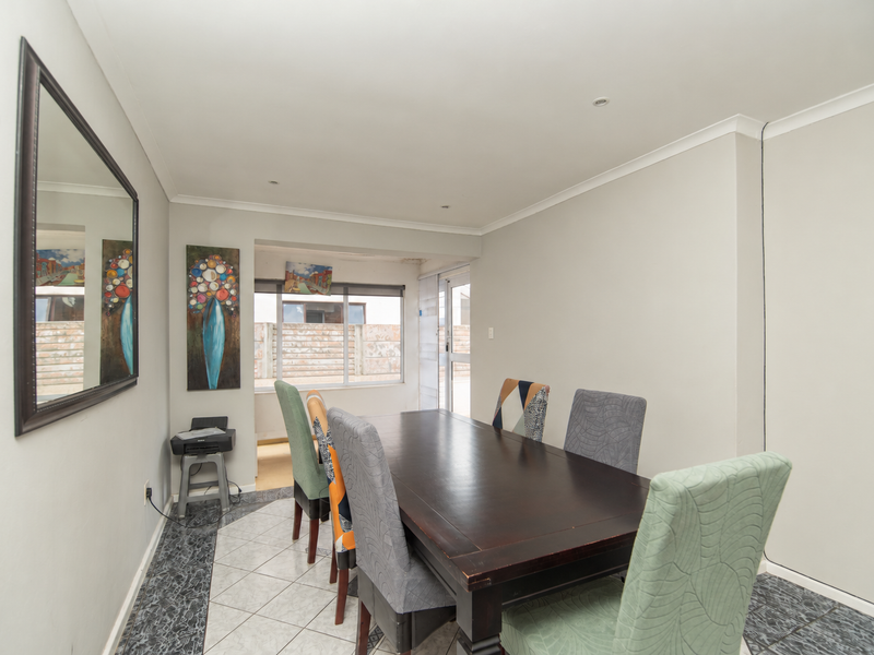 A dining room featuring tiled flooring, recessed downlighting, and a sliding glass door providing access to the exterior.