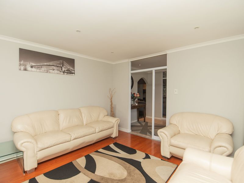 A comfortable living room featuring hardwood flooring, recessed downlighting, and a sliding glass door providing access to the adjacent area.