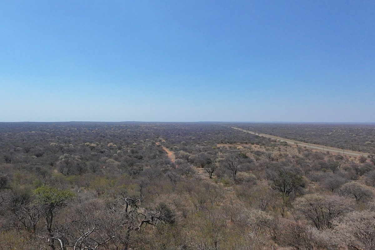 An expansive aerial view of the surrounding farm landscape, showcasing the vast natural terrain and open horizon.