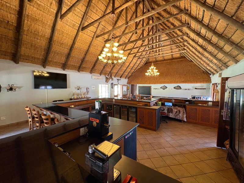Spacious bar area featuring a high vaulted thatched roof with exposed timber trusses, tiled flooring, and a large built-in service counter.