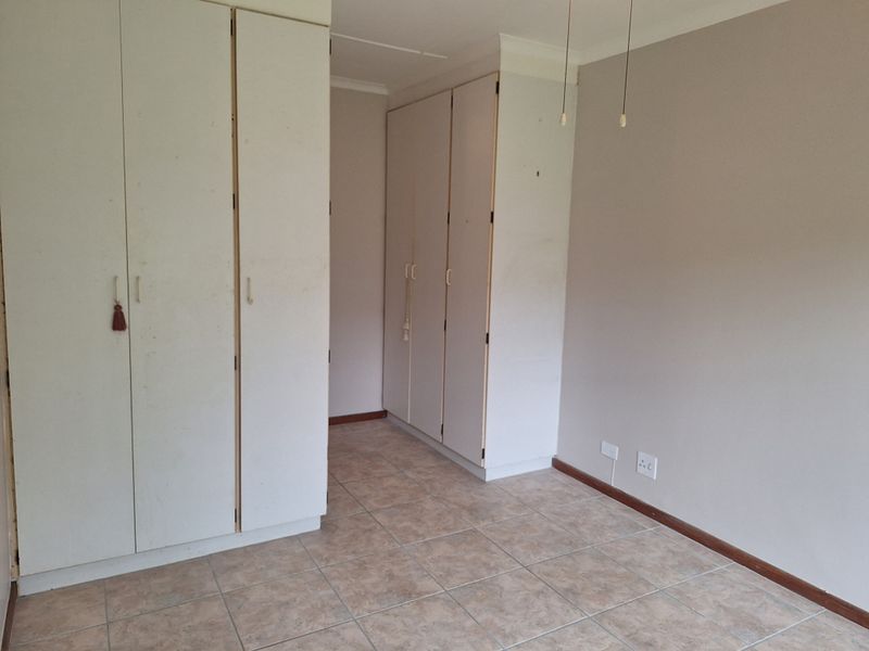 An empty bedroom featuring tiled flooring and built-in cupboards, offering a blank canvas for personalization and interior design updates.