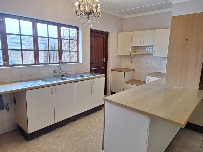 A functional kitchen featuring laminate countertops, double basin sink, and ample built-in cabinetry, awaiting modern updates to enhance its aesthetic appeal.