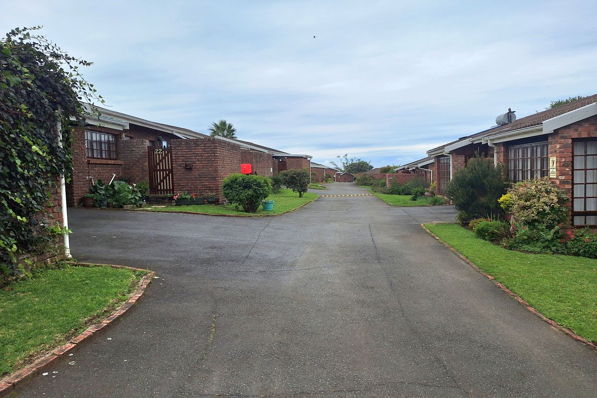 A view of the complex driveway and brick townhouse facades with established landscaping and paved access.