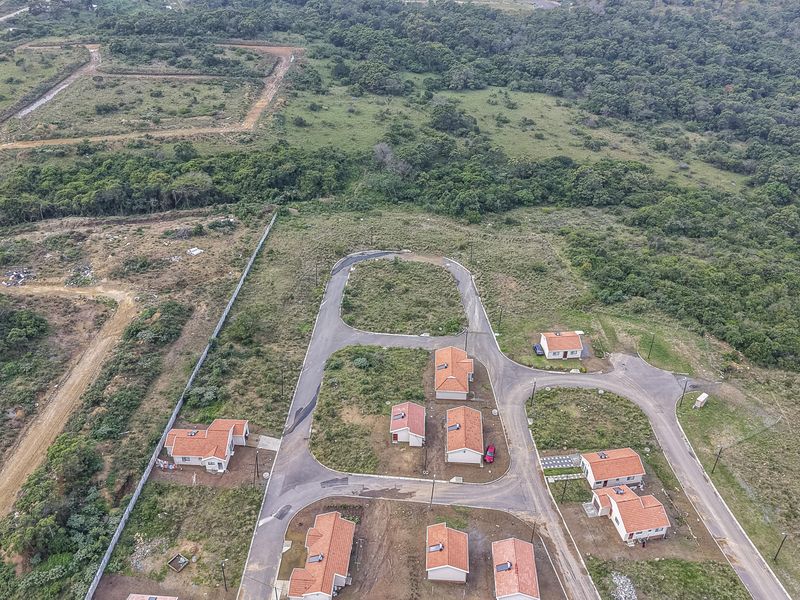 Aerial view of a residential development featuring multiple detached homes, paved internal roads, and surrounding natural vegetation.