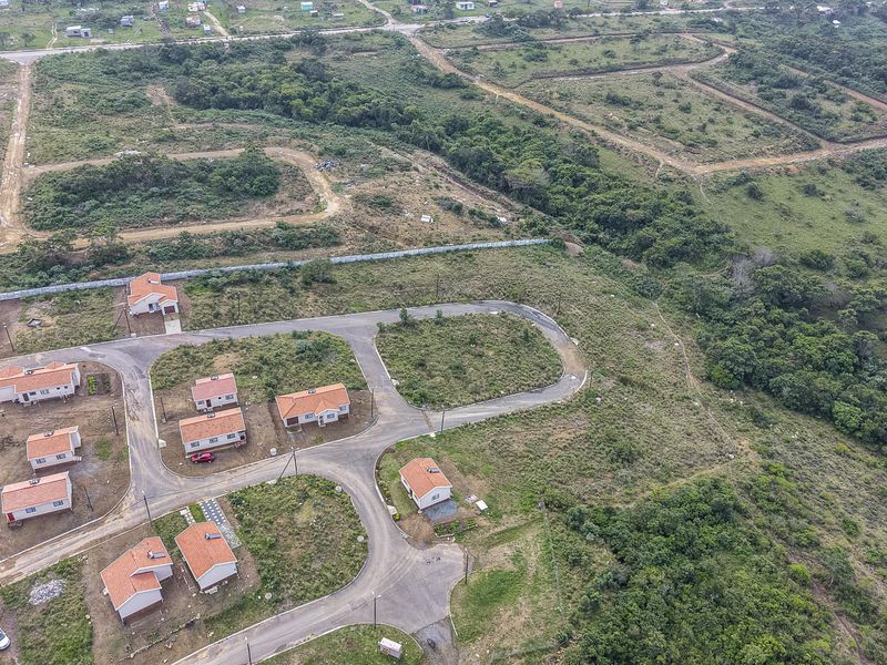Aerial view of a residential development featuring multiple detached homes, paved internal roads, and surrounding natural landscape.