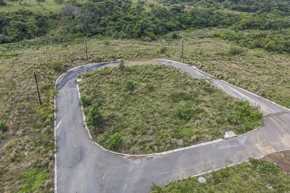 Aerial view of a vacant residential plot featuring a paved cul-de-sac, established kerbing, and street lighting infrastructure within a natural landscape setting.