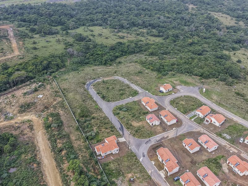 Aerial view of a residential development featuring established paved roads, street lighting, and multiple residential plots with existing housing units.