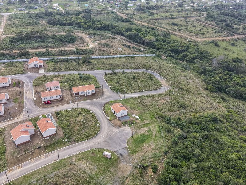 Aerial view of a residential development featuring paved roads, street lighting, and multiple detached houses situated on individual plots.