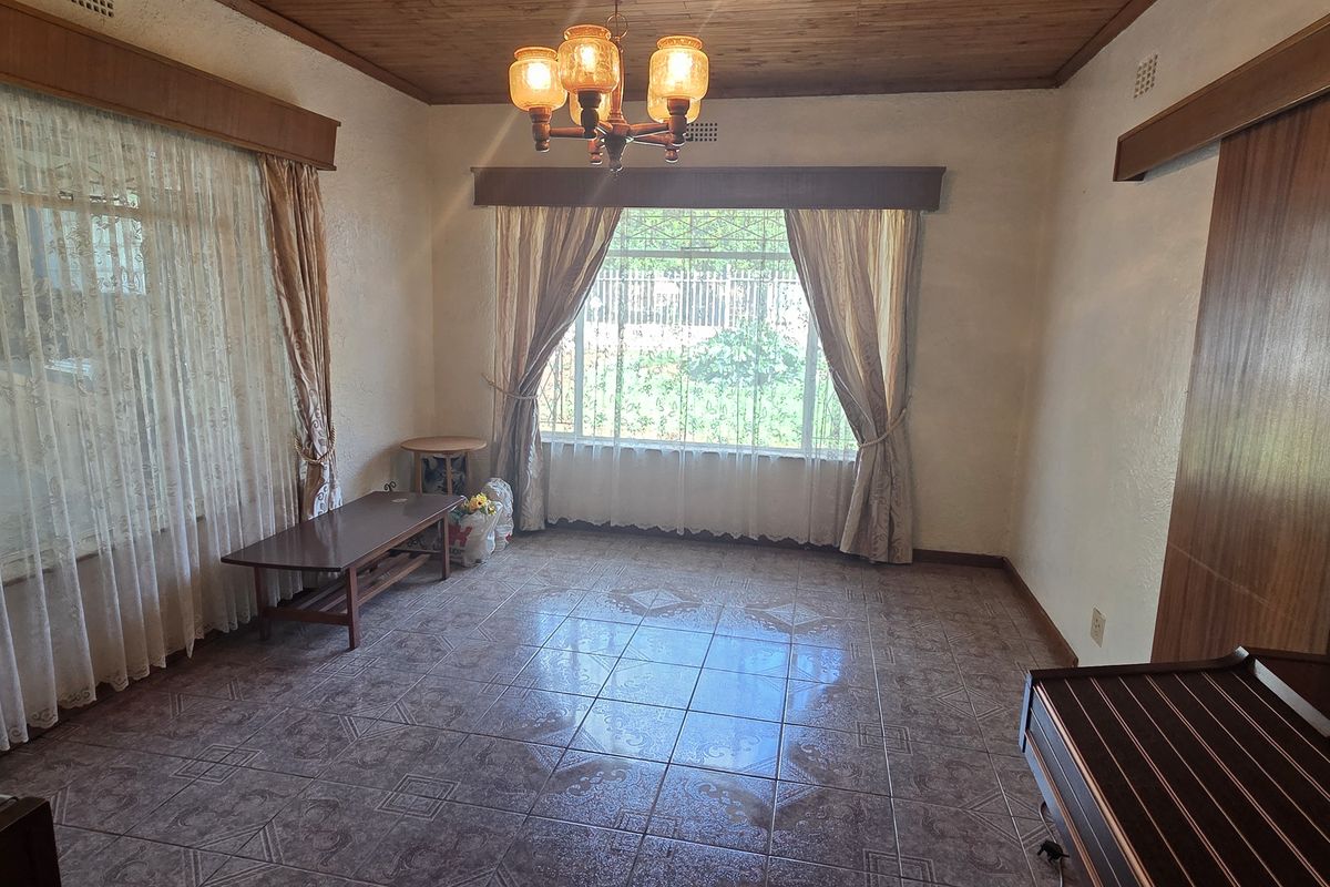 A spacious living room featuring timber ceilings, tiled flooring, and large windows that provide ample natural light.