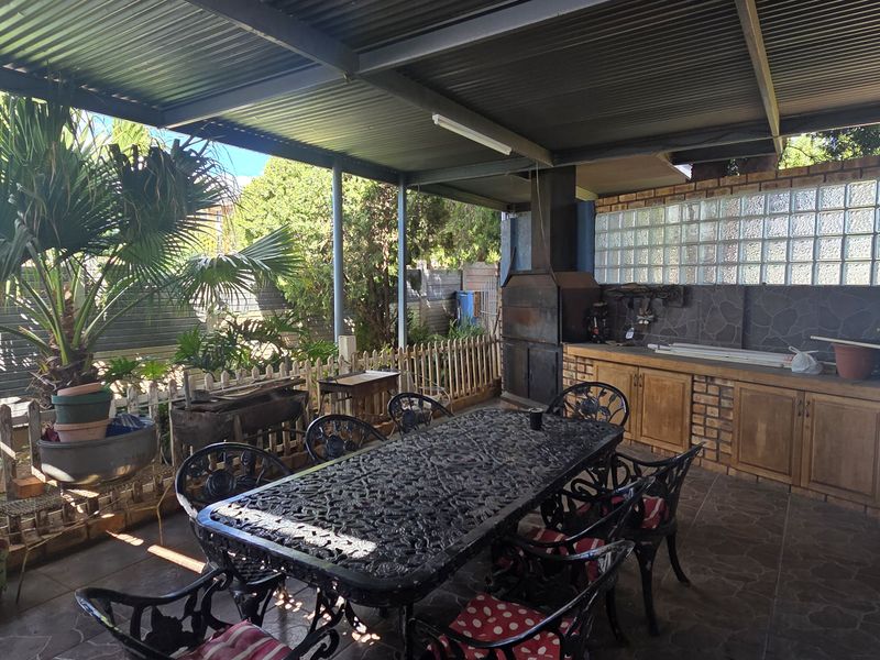 Covered outdoor patio featuring a built-in braai, brick cabinetry, and glass block wall, providing a functional space for outdoor entertaining.