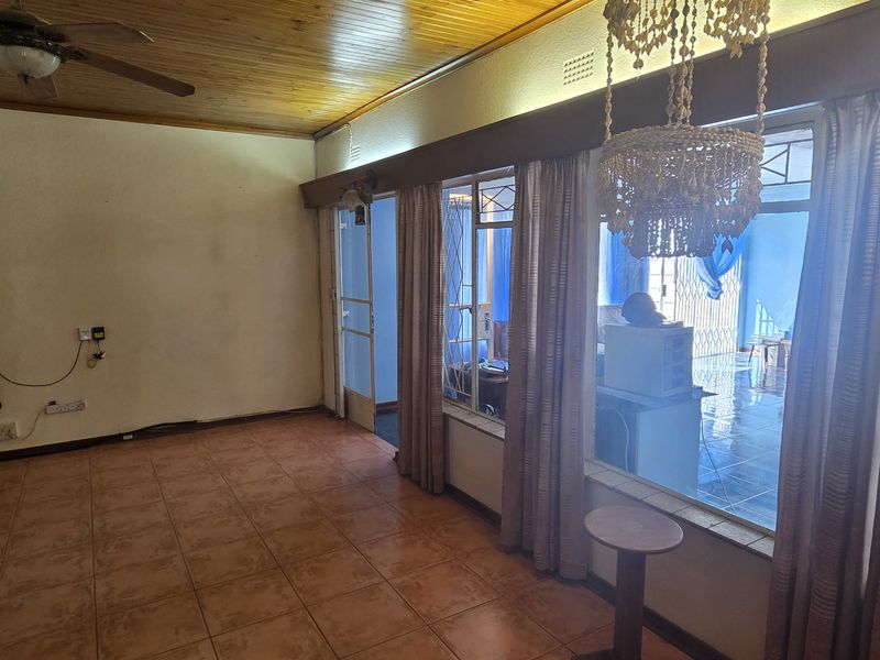 Spacious living area featuring timber ceilings, tiled flooring, and large sliding glass doors leading to an adjacent room.