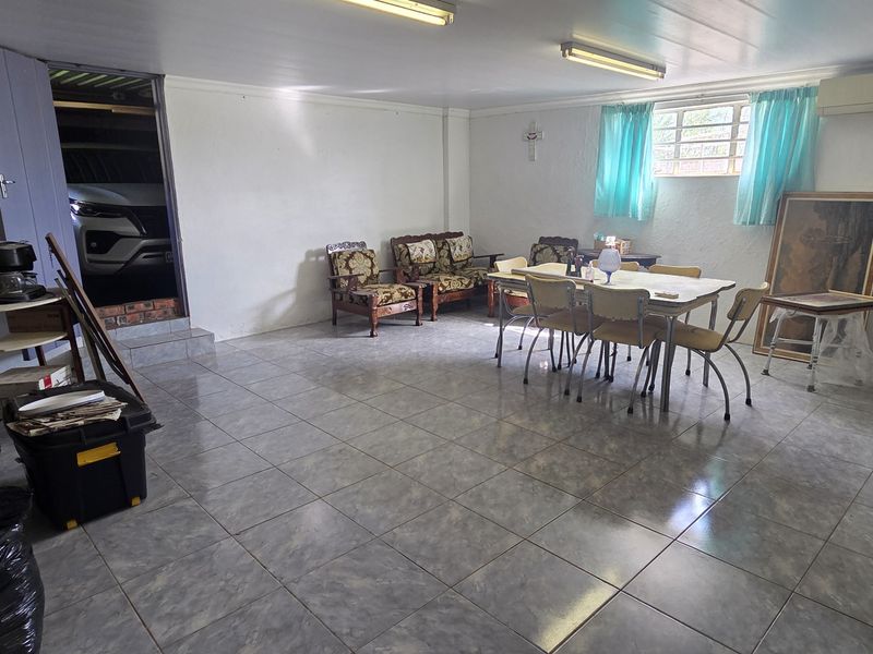 Spacious open-plan living and dining area featuring tiled flooring, split-system air conditioning, and direct access to the garage.