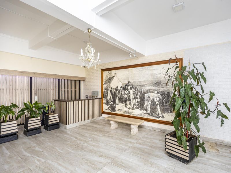 A spacious apartment building entrance lobby featuring a reception desk, tiled flooring, and decorative wall finishes.