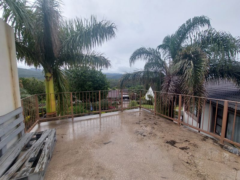 An elevated outdoor balcony featuring a metal balustrade and concrete flooring with scenic views of the surrounding landscape.