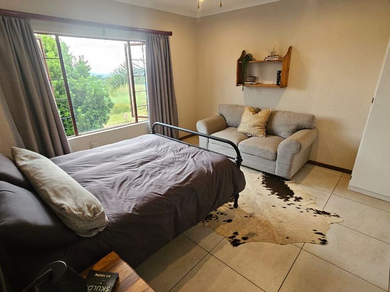 A bedroom featuring tiled flooring, a built-in wardrobe, and a large window providing natural light and garden views.