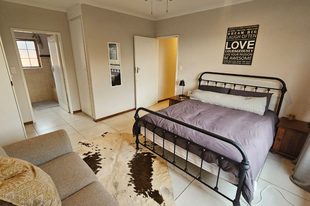 A spacious bedroom featuring tiled flooring, built-in cupboards, and direct access to an en-suite bathroom.