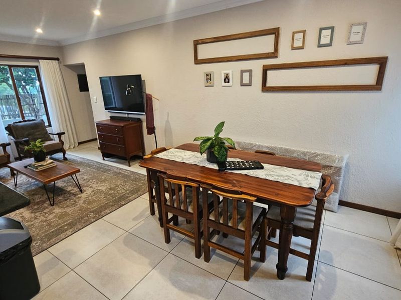 Open-plan living and dining area featuring neutral tiled flooring, recessed lighting, and a sliding glass door providing access to the outdoor space.
