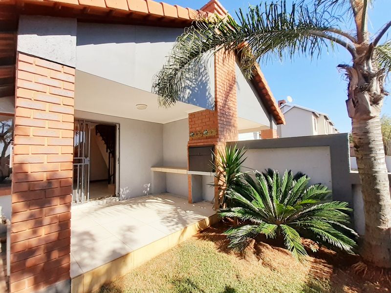 Covered patio area featuring a built-in braai, tiled flooring, and brick structural pillars, providing a functional outdoor entertainment space.
