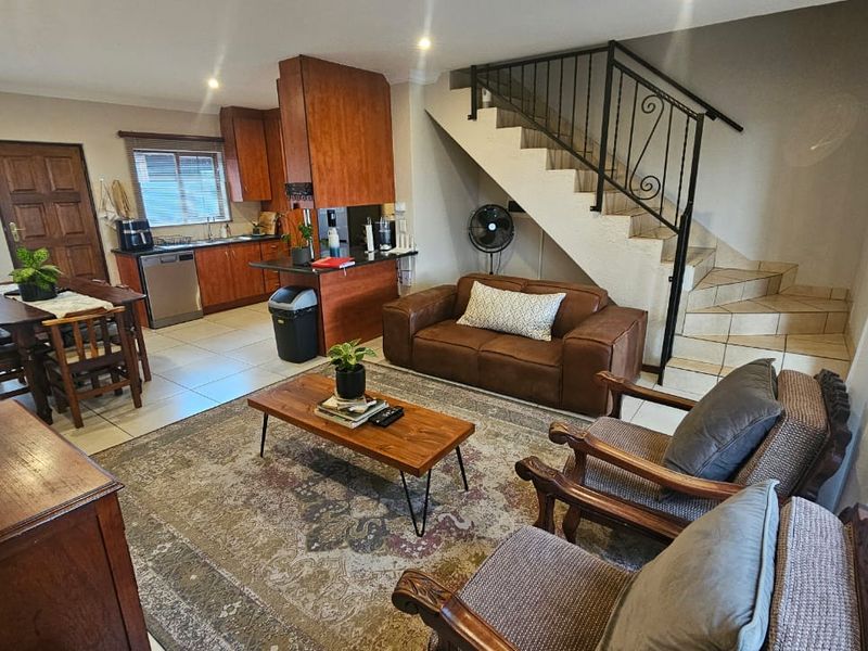 Open-plan living and kitchen area featuring tiled floors, built-in cabinetry, and a staircase with a decorative wrought iron railing.