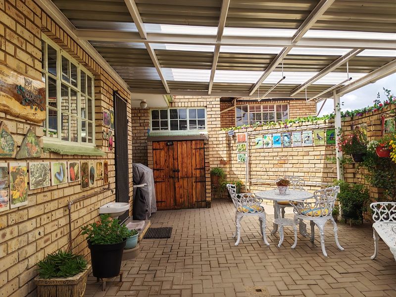 A covered outdoor patio area featuring facebrick walls, durable brick paving, and a translucent roof structure, providing a functional space for outdoor relaxation.