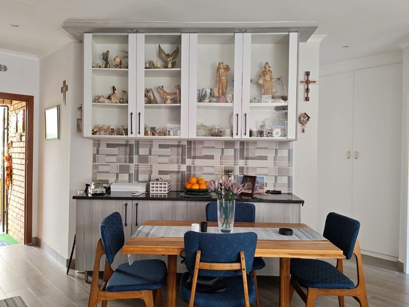 A dining area featuring built-in cabinetry with glass-fronted display units, a granite countertop, and a decorative tiled backsplash, providing ample storage and display space.